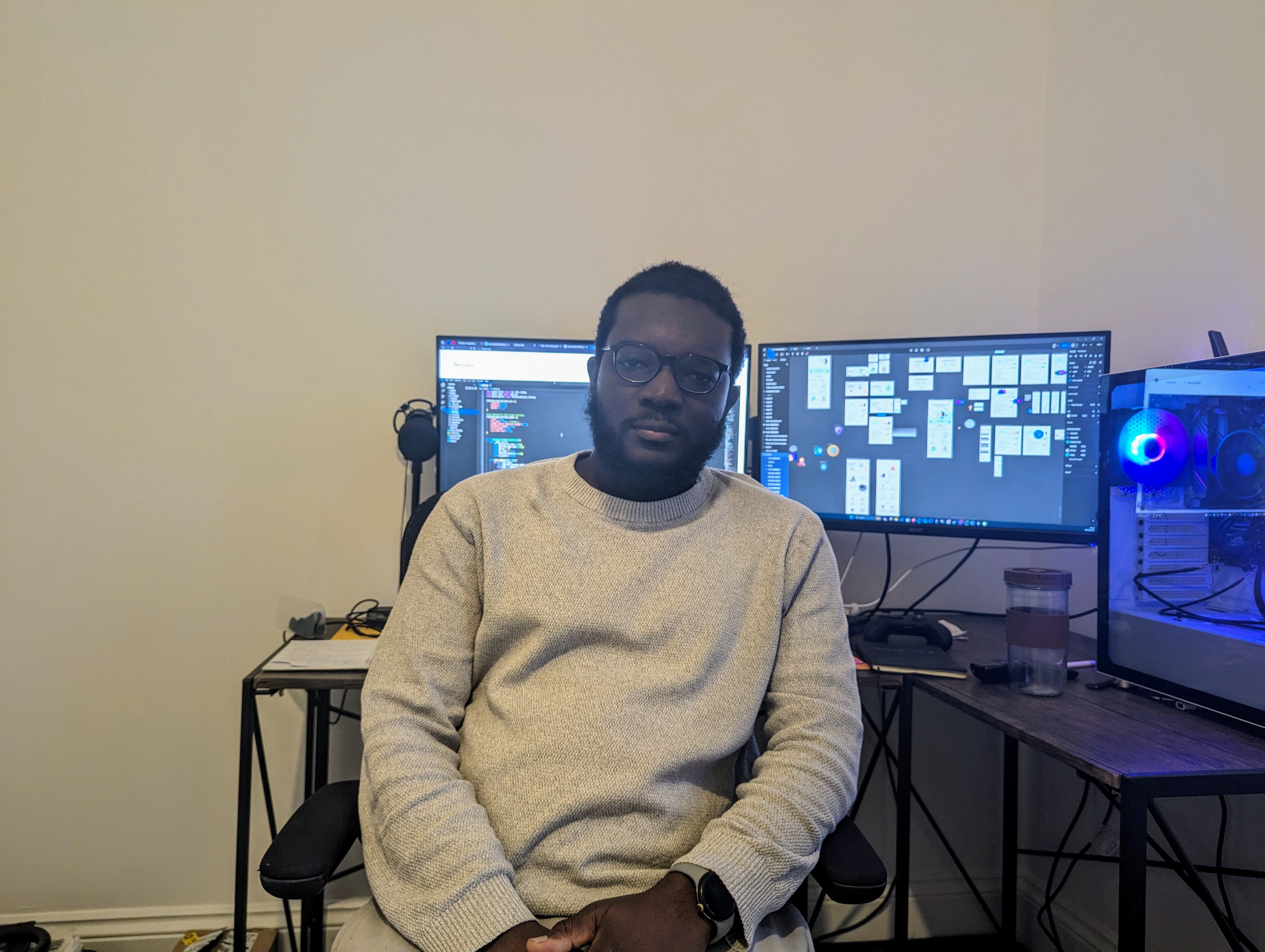 Professional workspace setup showing Aliyu at his desk with multiple monitors displaying development tools and cybersecurity applications, representing consulting and professional services